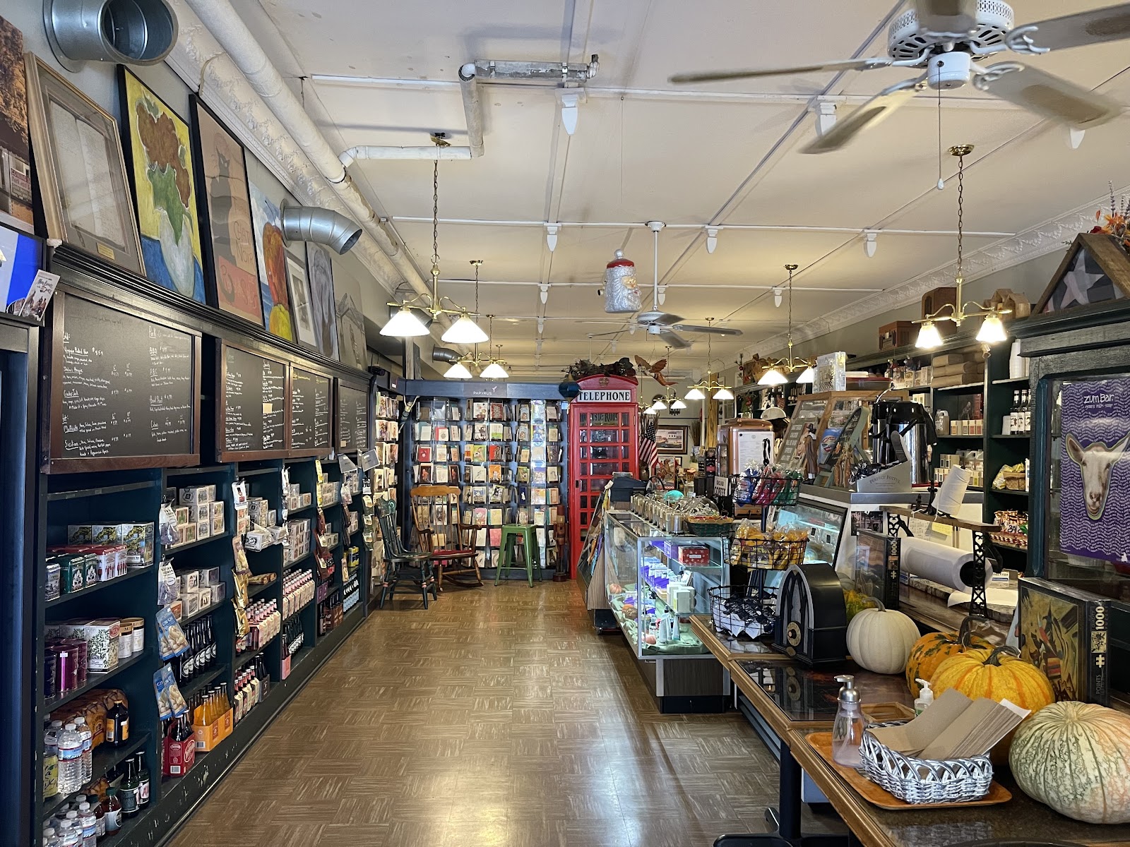 The eclectic interior of Gardner's Market with bookshelves, a red phone booth, and a glass deli case
