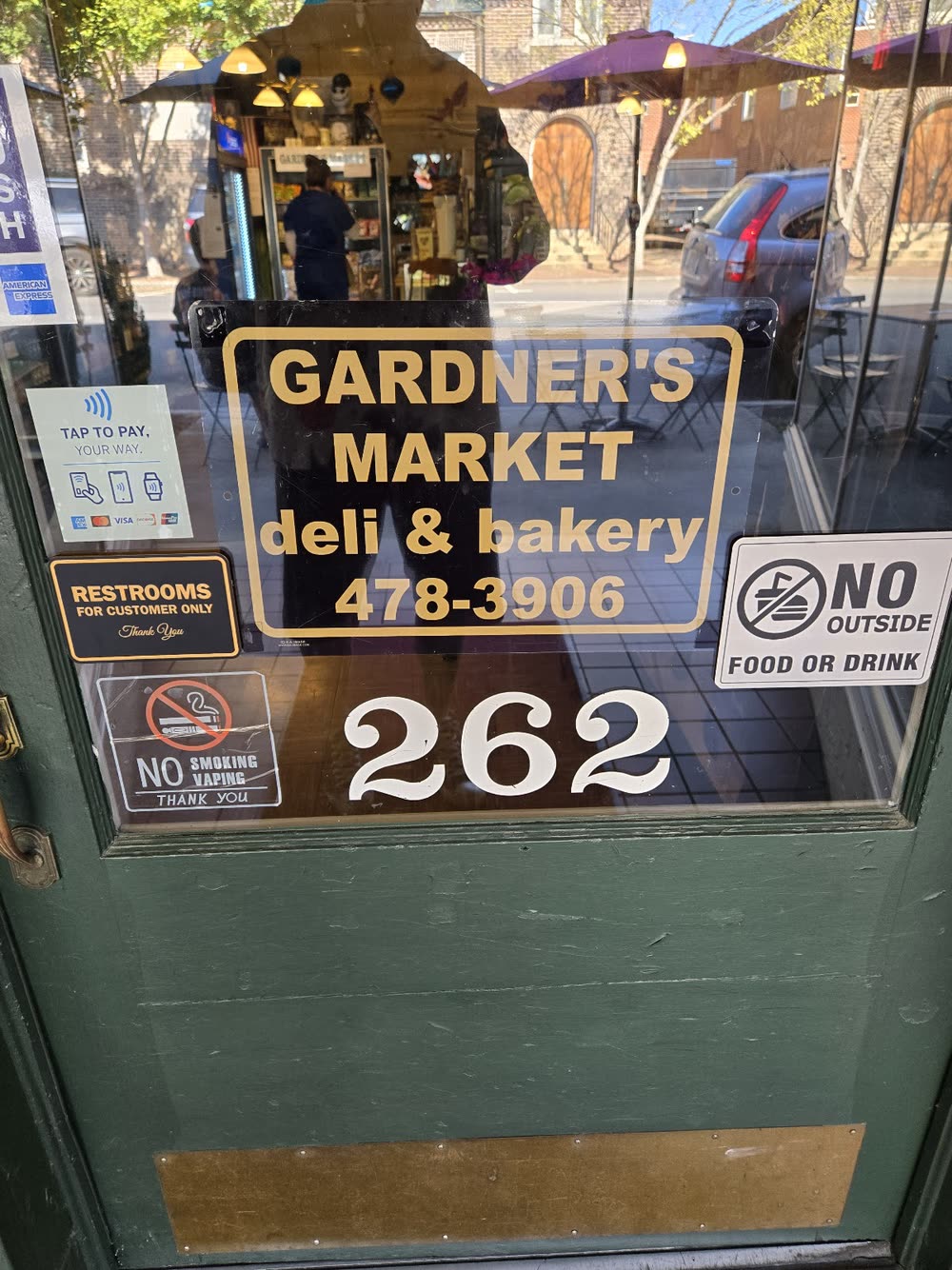 The front door of Gardner's Market with the gold deli and bakery sign and street number 262